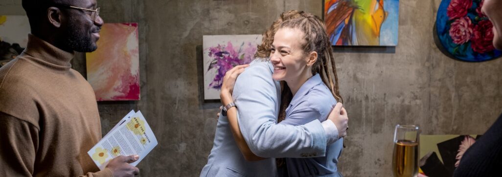 Happy young female embracing modern artist in gallery